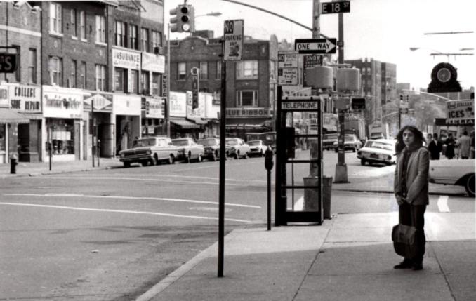 Jill Slaughter as teenager on street corner, standing in front of telephone booth in Brooklyn near train station