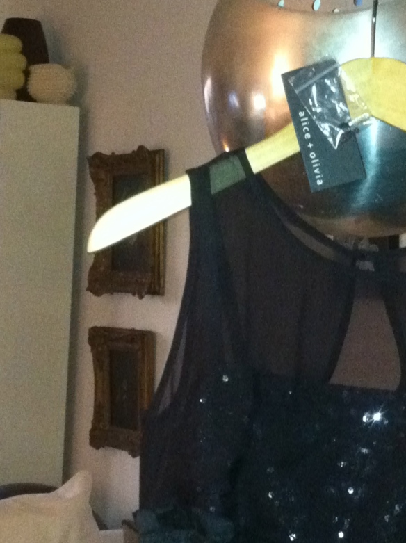 Black party dress with extra button in a plastic bag on a hanger